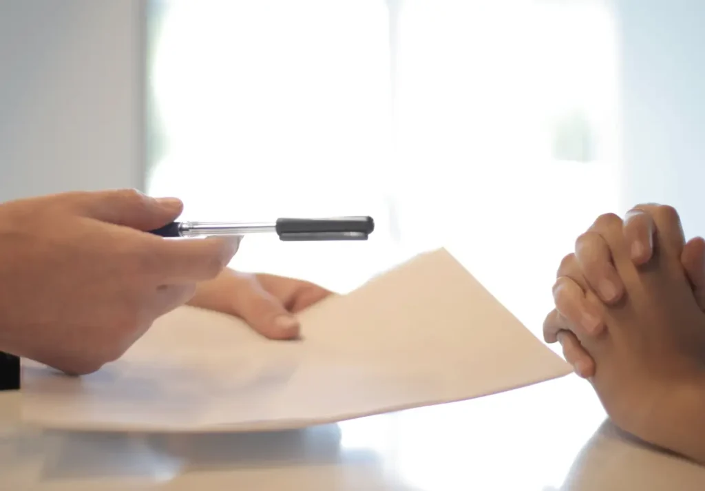Recepcionista entregando caneta para aluno de academia assinar o contrato